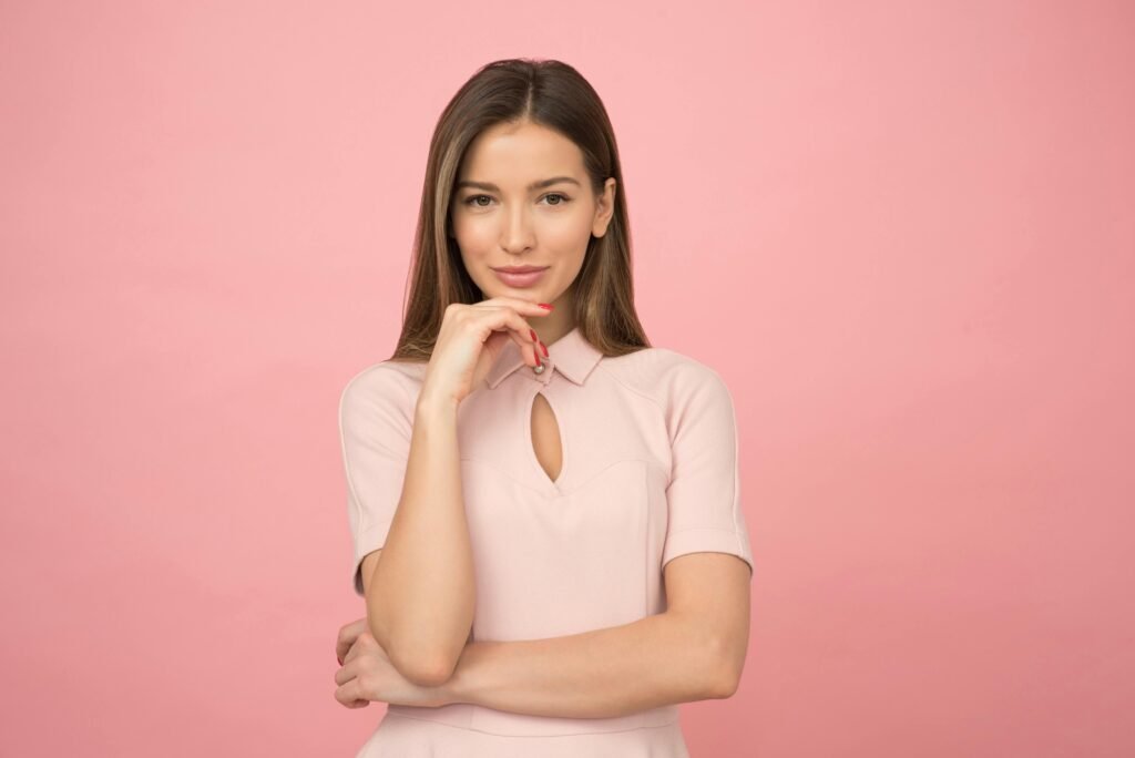 pexels-photo-1036623-1036623 Portrait of a young woman posing elegantly in a studio with a pink background.